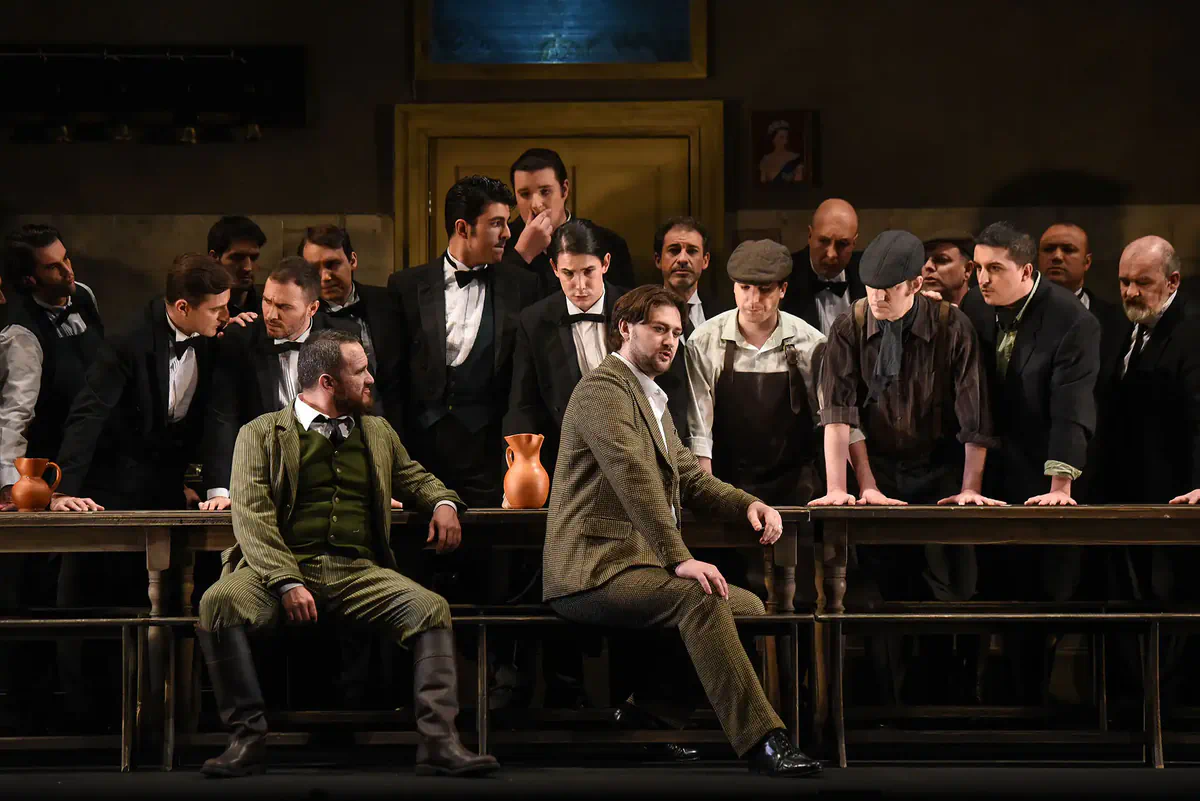 Escena de Lucia di Lammermoor con varios intérpretes reunidos alrededor de una larga mesa.